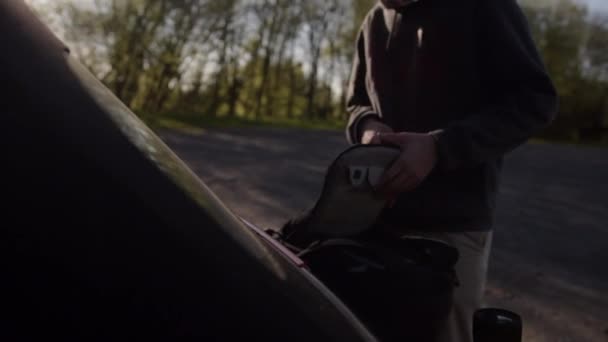 SLOW MOTION: Young Guy Packing his Packpack in Trunk of Car in Beautiful Summer Light — Stock Video