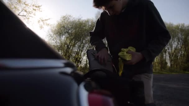 SLOW MOTION: Jovem embalando seu pacote em tronco de carro na bela luz de verão — Vídeo de Stock