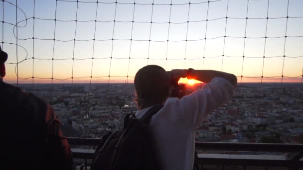 LOW MOTION: Fotógrafo caucasiano tirando fotos em um telhado do pôr do sol no verão — Vídeo de Stock