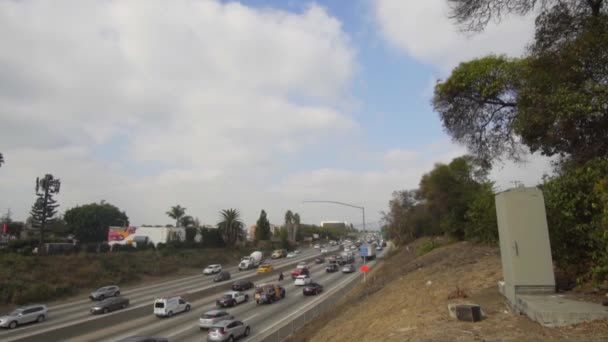 SLOW MOTION: Pan down op drukke snelweg verkeer in Los Angeles op bewolkte blauwe hemel dag — Stockvideo