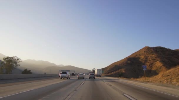 Gyönyörű kilátás a forgalomra a kaliforniai autópályán sivatagi táj és hegyek napnyugta — Stock videók