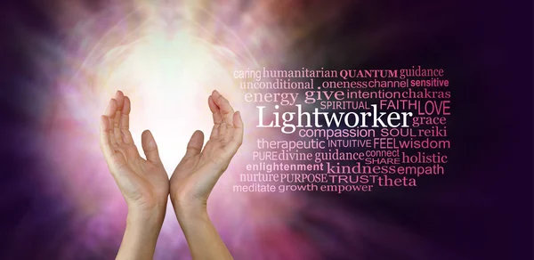 The healing hands of a Lightworker - Female hands in an upwards open gesture beside the word LIGHTWORKER and a relevant word cloud  on a radiating pink coloured energy background