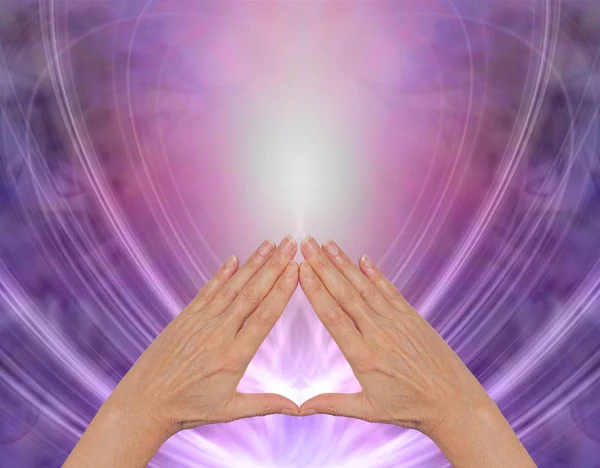 Working with Pyramid Healing Energy - female hands making a triangle shape on a magenta purple flowing triangular shaped energy field with plenty of copy space above