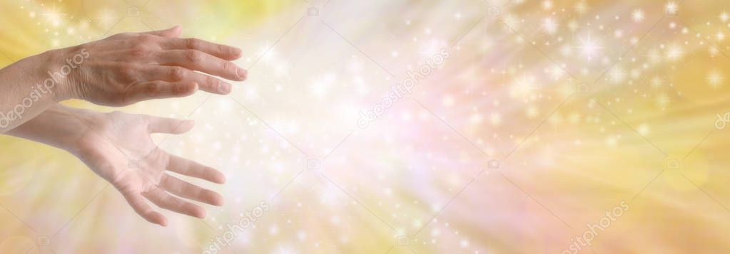 Sending out beautiful golden healing energy - female hands with sparkling white light flowing outwards against a wide golden orange yellow flowing energy background with copy space