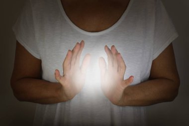 Şifacı, insan elektromanyetiğini ellerle nasıl hissedeceğini gösteriyor. Beyaz bluzlu bir kadın, beyaz bir enerji topuna sarılmış. 