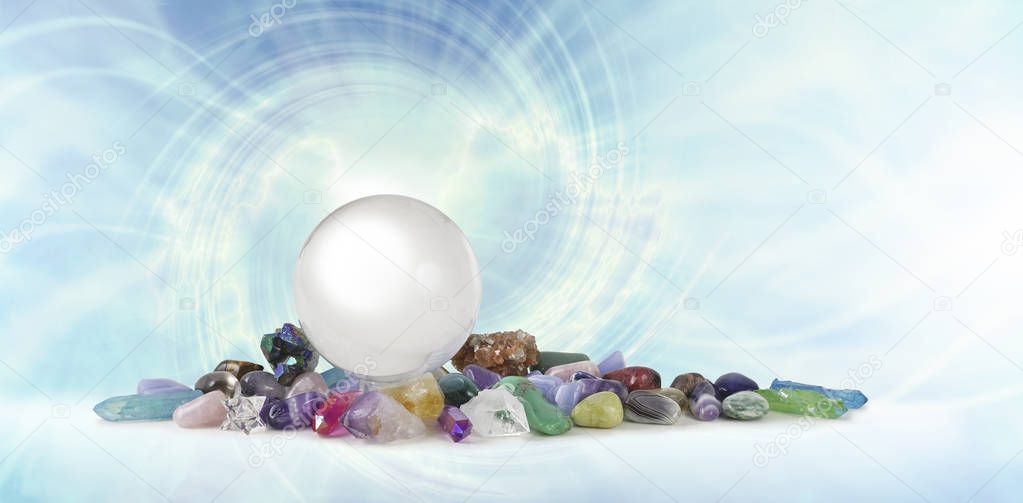 Magical Healing Crystal Vortex Background - a large clear crystal ball atop a selection of healing crystal stones against a pale blue spiralling vortex with copy space