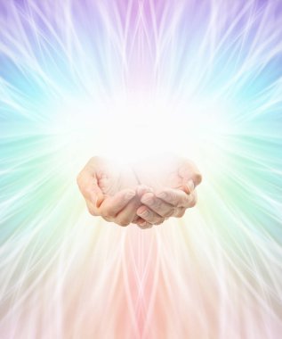 Using colour healing full spectrum energy background - female cupped hands with rainbow coloured light flowing out in all directions from central white orb light and copy space all around