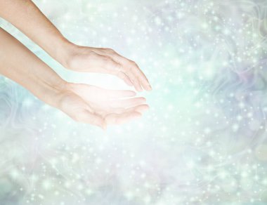Healer basking in sparkling white light  -  female hands reaching into a soft pale green sparkling energy  field with white light and copy space clipart