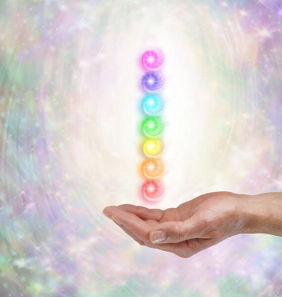   Male healer with Seven Spinning Chakras  - male open palm hand  and stack of seven vortexing chakras hovering above on an ethereal energy formation background with copy space                             