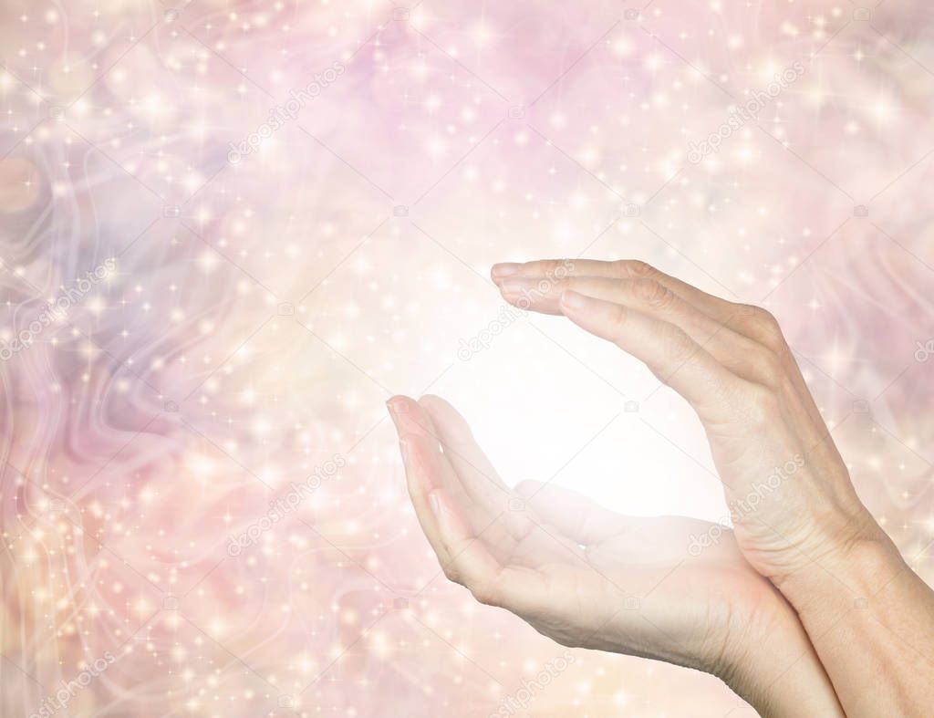 Healer connecting with Unconditional Love Healing Energy - cupped female hands inside a peach flesh coloured shimmering sparkling energy field holding a ball of white energy