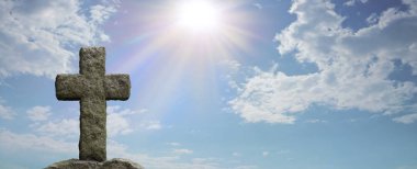 Lent Cross and God's Light - Rugged stone cross in foreground with a bright blue sky and sun burst shining down providing copy space on the right for messages 