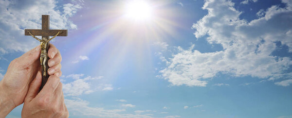Отражение и подготовка к постленному баннеру сообщений - руки, держащие деревянное распятие на широком красивом голубом фоне облаков неба, обеспечивая пространство для копирования религиозных целей
  