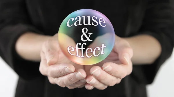 Nothing escapes cause and effect - female with cupped hands and a rainbow coloured transparent bubble containing the words CAUSE & EFFECT