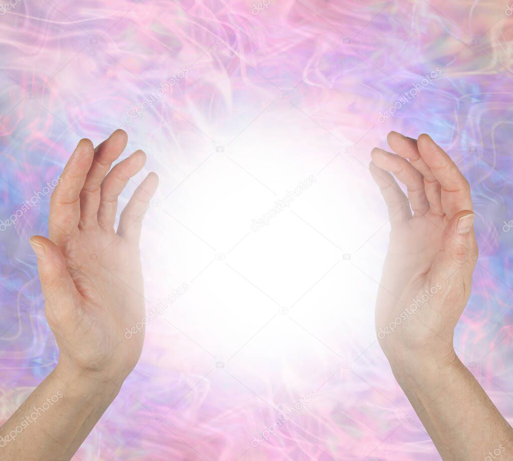 Sensing spiritual healing energy field between hands - female hands 25cm apart opposite each other with a bright white light orb energy between against a pale pink purple energy field  background 