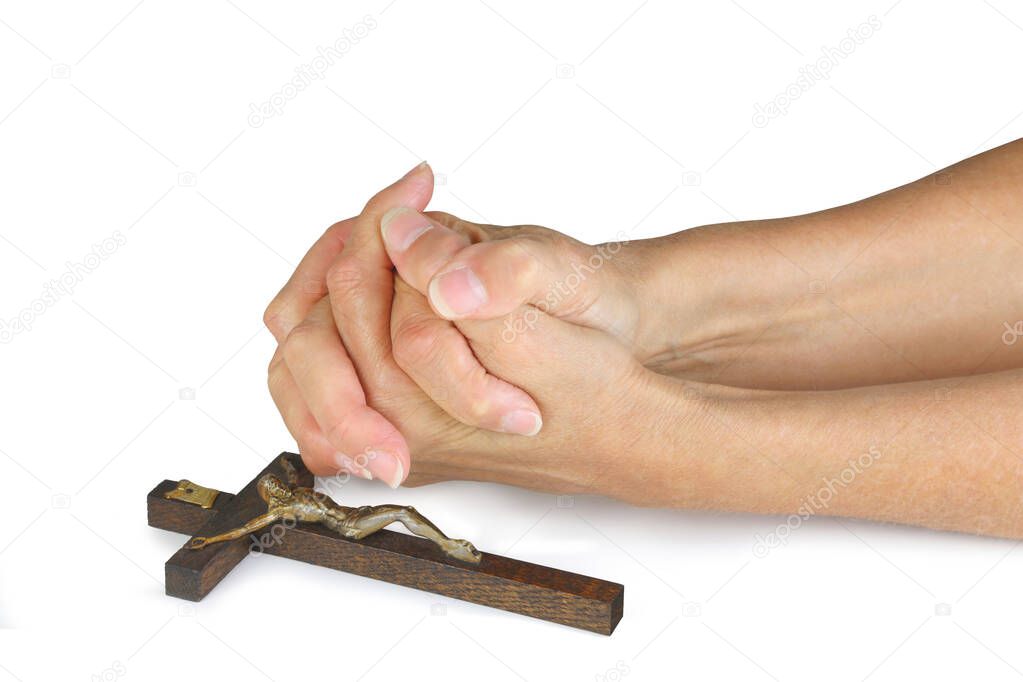 Praying for Peace this Easter - female hands in prayer position laid next to a wooden crucifix isolated on a white background