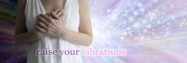 Raise your vibrations healing concept banner - female torso in white robes with hands laid over heart against a wide dark to light spiritual sparkling energy background and the words RAISE YOUR VIBRATIONS clipart