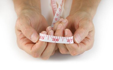 Hangi bel ölçüsünde olmak isterdiniz? 36 'da beyaz arka planda izole edilmiş bir mezura tutan kadın elleri.