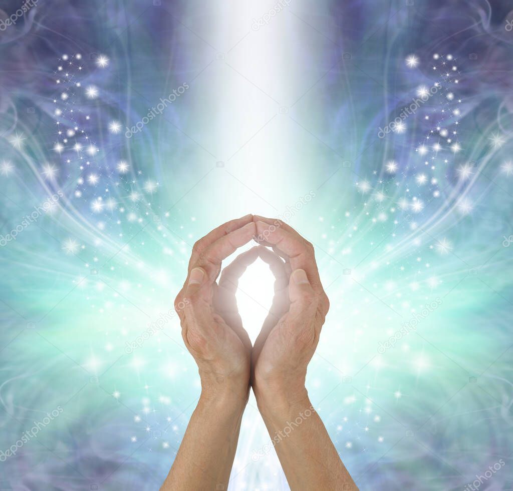 Distant Healer sending Energy out where needed - female hands with cupped fingertips touching on an explosion of sparkles against hues of blue background and a shaft of white light plus copy space above