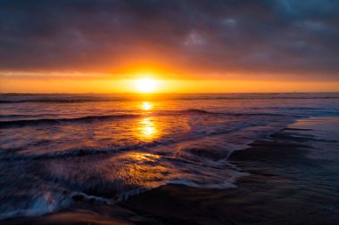 Dalgalar sahile çarptığında güneş batıyor..