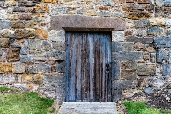 Old entrance to a castle with a wooden door and brick walls