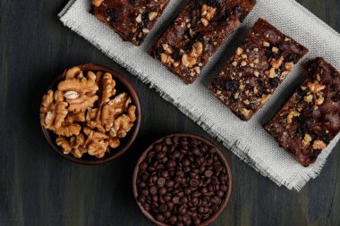Çikolatalı browni ve cevizlerin yanında ceviz ve öndeki kil kaplarda çikolata, evdeki karantina sırasında sağlıklı yiyecekler.
