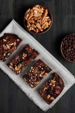 Çikolatalı browni ve cevizlerin yanında ceviz ve öndeki kil kaplarda çikolata, evdeki karantina sırasında sağlıklı yiyecekler.