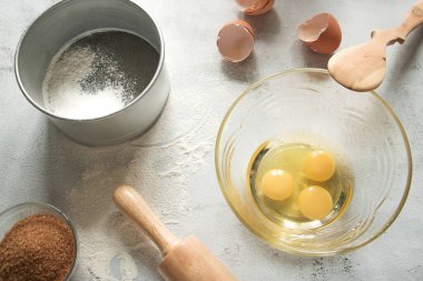 Cam kasede yumurta, merdane, esmer şeker, un süzgeci ve yumurta kabuğu.