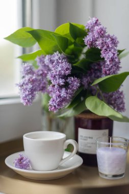 Kahvaltıda. Sütlü kahve, mumlar, penceresinde tepsi ve leylak çiçekleri. - Günaydın. Evde kal. İzolasyon. Meditasyon.