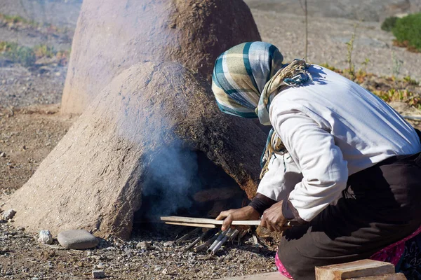 Elderly woman cooks in old traditional Moroccan earth ovens made of sandstone and mud