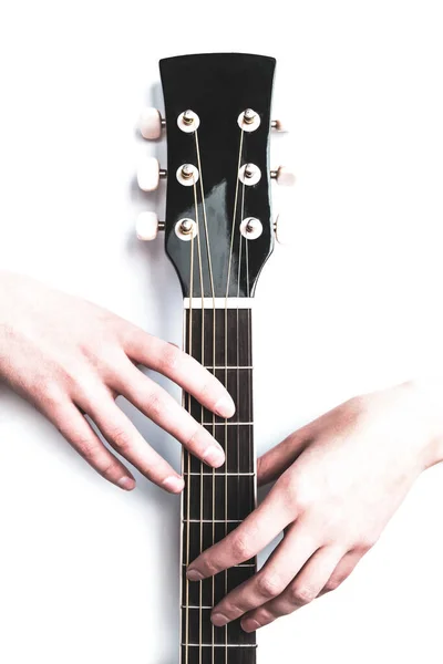 women\'s hands hold a six string acoustic guitar