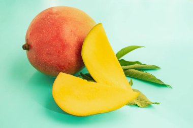 Olgun mango ve dilimlenmiş yeşil arkaplan parçaları