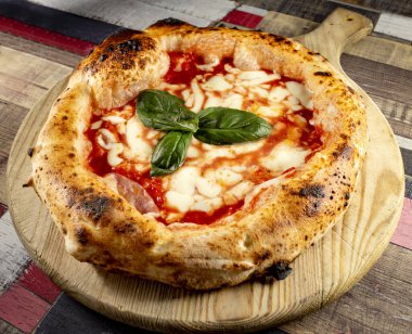 Tahta bir masanın üzerinde doğranmış İtalyan pizzası