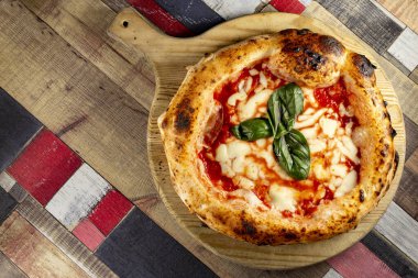 Tahta bir masanın üzerinde doğranmış İtalyan pizzası