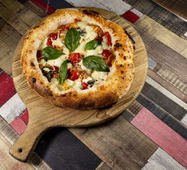 Tahta bir masanın üzerinde doğranmış İtalyan pizzası