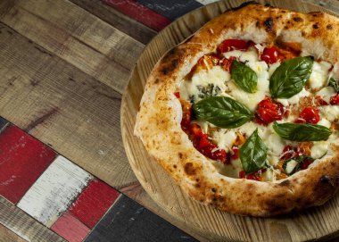 Tahta bir masanın üzerinde doğranmış İtalyan pizzası