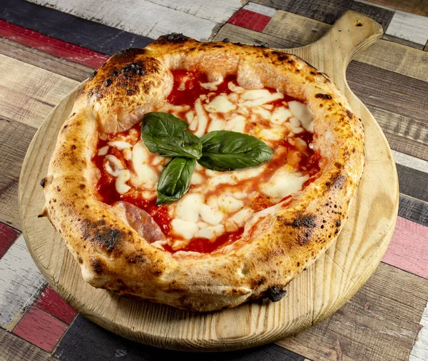 Tahta bir masanın üzerinde doğranmış İtalyan pizzası