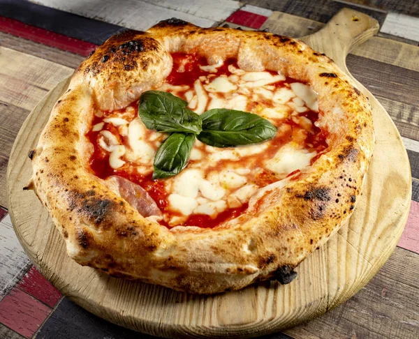 Tahta bir masanın üzerinde doğranmış İtalyan pizzası