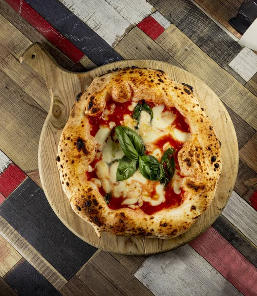 Tahta bir masanın üzerinde doğranmış İtalyan pizzası