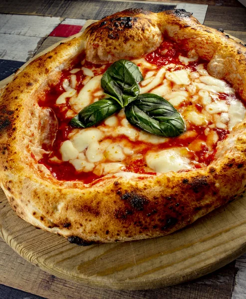 Tahta bir masanın üzerinde doğranmış İtalyan pizzası
