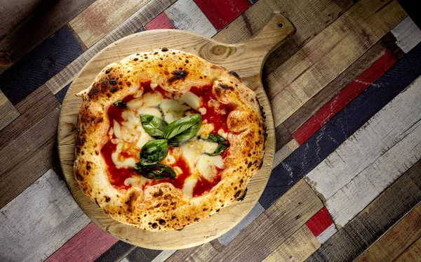 Tahta bir masanın üzerinde doğranmış İtalyan pizzası
