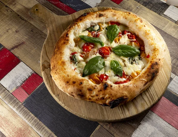 Tahta bir masanın üzerinde doğranmış İtalyan pizzası