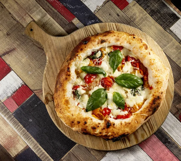 Tahta bir masanın üzerinde doğranmış İtalyan pizzası