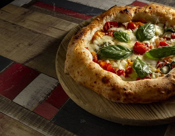 Tahta bir masanın üzerinde doğranmış İtalyan pizzası