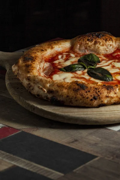 Tahta bir masanın üzerinde doğranmış İtalyan pizzası