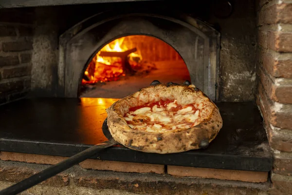 Tahta bir masanın üzerinde doğranmış İtalyan pizzası