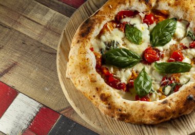 Tahta bir masanın üzerinde doğranmış İtalyan pizzası