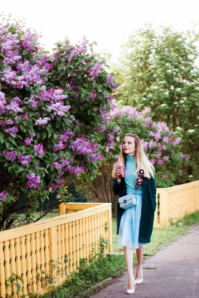 Hermosa mujer está caminando por el callejón lila en el campo en primavera . —  Fotos de Stock