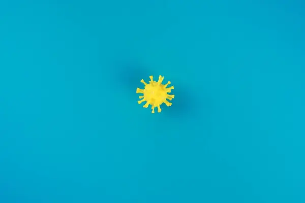 Símbolo amarillo covid-19 en el fondo azul. Copiar espacio, patrón . — Foto de Stock