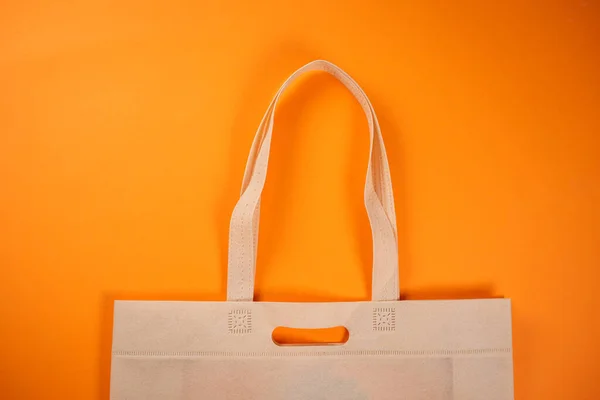 Fabric textile shopping bag on the orange background. Consumer help.