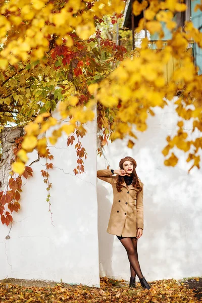 Stilvolle Frau, die im Herbst Zeit im Freien verbringt. Gelbe Bokeh-Blätter vorne. — Stockfoto